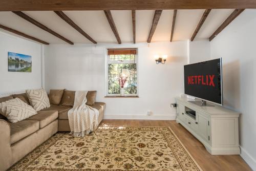 a living room with a couch and a flat screen tv at Bard's Cottage in Alcester