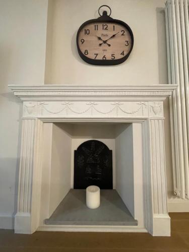 a clock on the wall above a fireplace with a candle at La Dimora del Brocante in Cuneo