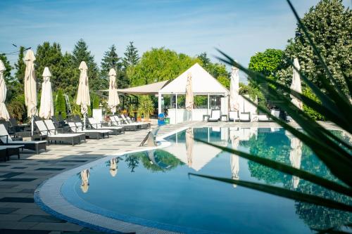 una piscina en un complejo con sillas y sombrillas en Unique Garden Hotel, en Brăila