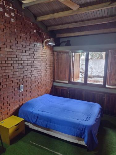 1 dormitorio con 1 cama azul en una pared de ladrillo en OlasHostel en Mendoza