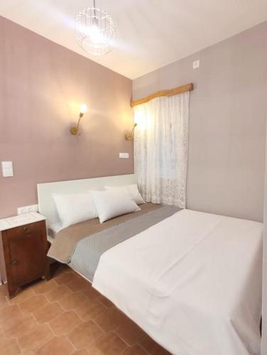a bedroom with a large white bed and a window at Village View House in Galissas
