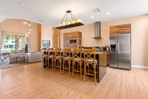 a kitchen with a bar with chairs and a refrigerator at 7594 Magic Village 3suites 6guets 8 min Disney in Orlando