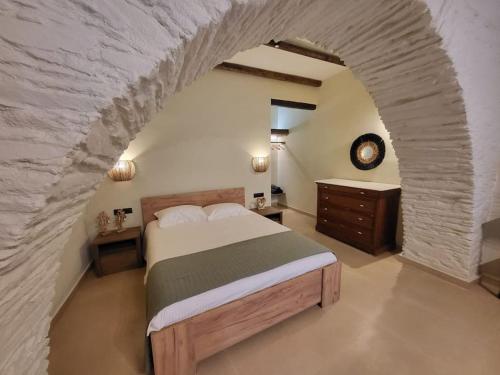 伊奧斯喬拉的住宿－Coucou Boutique Studio，一间卧室设有一张大床和石墙