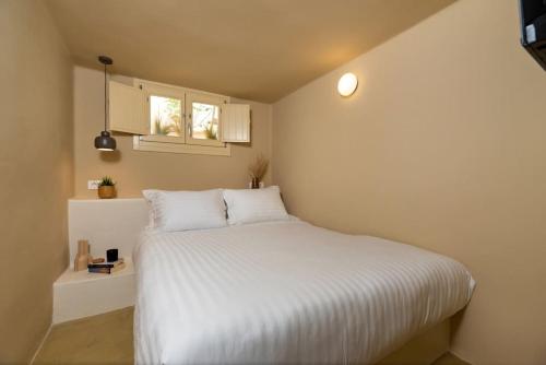 a bedroom with a bed with white sheets and a window at RockHill Luxury Suite Imerovigli in Fira