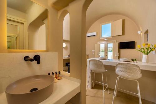 a bathroom with a sink and a counter with chairs at RockHill Luxury Suite Imerovigli in Fira