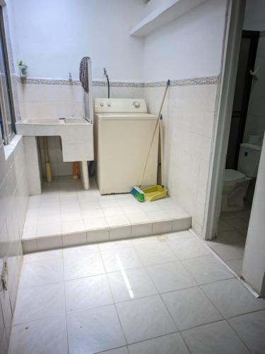 ein weiß gefliestes Bad mit einem Waschbecken und einer Waschmaschine in der Unterkunft Casa azul in Armenia