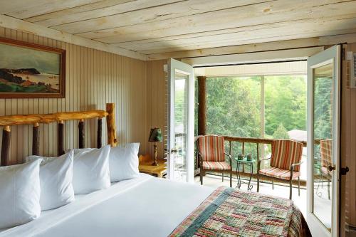 a bedroom with a bed and a balcony with chairs at Friends Lake Inn in Chestertown