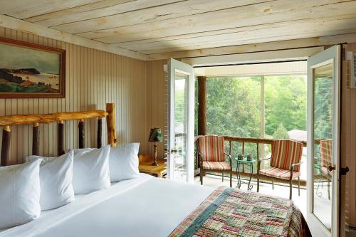 1 Schlafzimmer mit einem Bett und einem Balkon mit Stühlen in der Unterkunft Friends Lake Inn in Chestertown