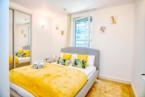 a bedroom with a large bed with a yellow blanket at Your gateway to London & Heathrow, Stylish flat near station in Hayes