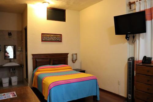 a bedroom with a bed and a flat screen tv at Hotel Zaragoza in Tepoztlán