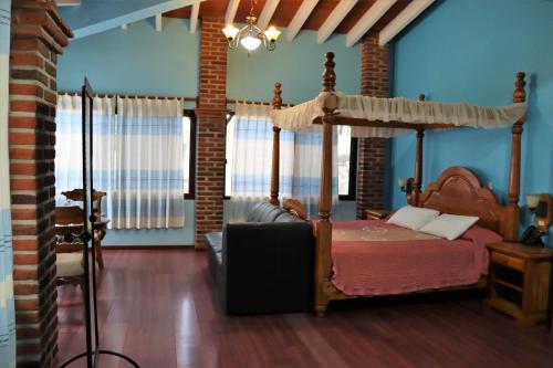 1 dormitorio con cama con dosel y paredes azules en Hotel Zaragoza, en Tepoztlán