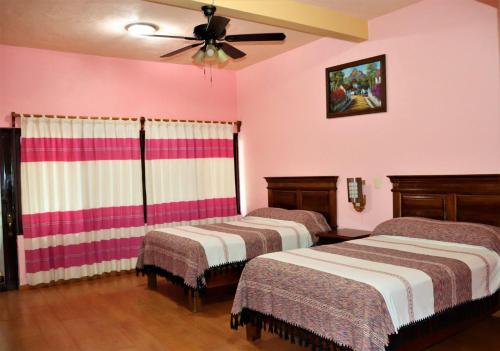 two beds in a room with pink walls at Hotel Zaragoza in Tepoztlán
