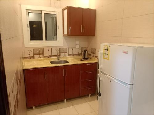 a kitchen with a sink and a white refrigerator at روائع الأحلام للاجنحة الفندقية in Jeddah