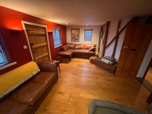 sala de estar con sofá, mesa y puerta en Hound and Human Holiday Cottage - Redgrave, Suffolk en Diss