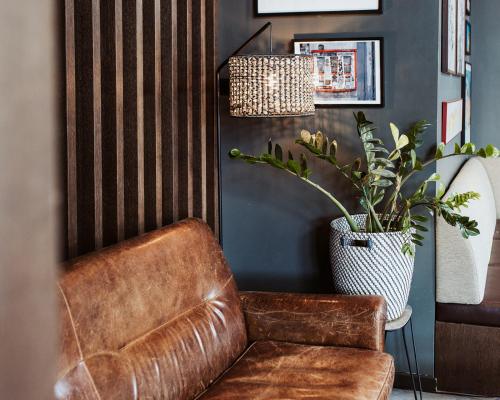 a brown leather chair in a room with a potted plant at Emma by Schulz Hotel Berlin Friedrichshain in Berlin