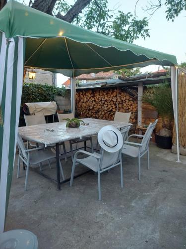 a table and chairs under a green umbrella at Вила Радеви in Obzor