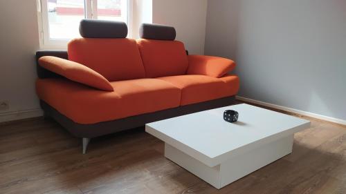 ein orangefarbenes Sofa im Wohnzimmer mit Couchtisch in der Unterkunft Appartement Fx 1 in Saint Die