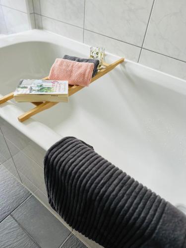 a bathtub with a black hose and a shelf next to a bath tub at Apartment Boho Living in Bautzen
