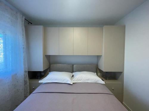 a bedroom with a bed with white cabinets at NeRi in Trogir