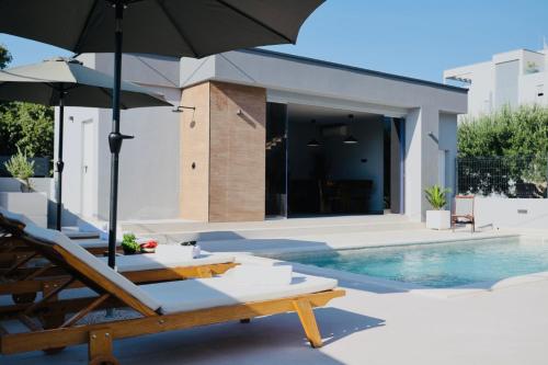 a swimming pool with chairs and umbrellas next to a house at Holiday Home TiA in Split