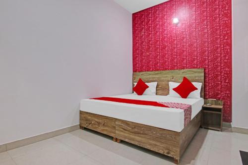 a bedroom with a bed with a red wall at OYO Flagship Hotel Suncity in Faridabad