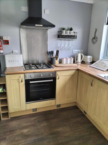 a kitchen with wooden cabinets and a stove top oven at Sea Shells in Torquay