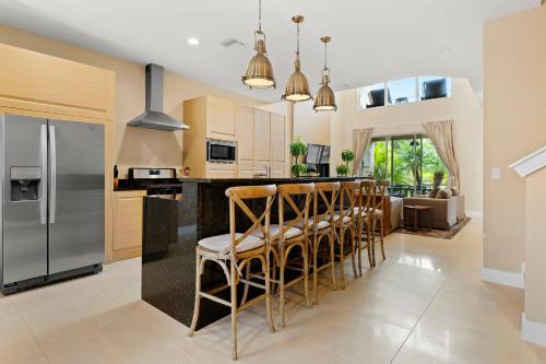 a kitchen with stainless steel appliances and a bar with stools at 7659 Magic Village Excellent 4 suites 6 min Disney in Orlando