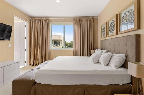 a bedroom with a large white bed with a window at 7659 Magic Village Excellent 4 suites 6 min Disney in Orlando