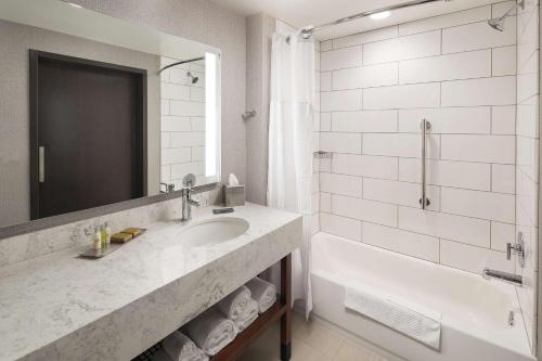 a bathroom with a sink and a tub and a shower at Doubletree By Hilton Greeley At Lincoln Park in Greeley