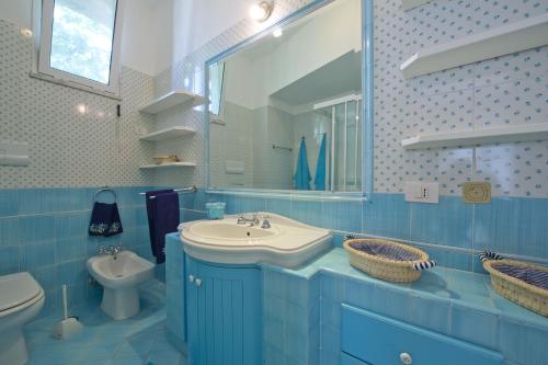 a blue bathroom with a sink and a toilet at Villa Giulia in Praiano