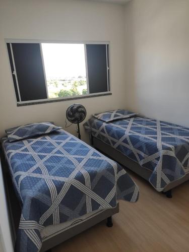 two beds in a room with two windows at Aruana Azul 502 - Apto com AR, PISCINA, Varanda Integrada - Aluguel por Temporada in Aracaju