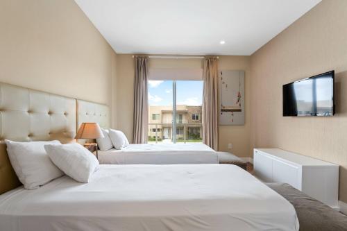 a hotel room with two beds and a television at 3212 Magic Village 8 guests lakefront 8 min Disney in Orlando