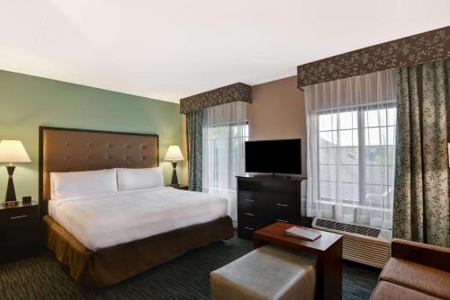 a hotel room with a bed and a flat screen tv at Homewood Suites by Hilton Aurora Naperville in Aurora