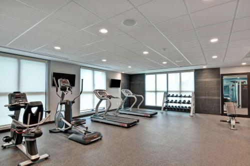 a gym with cardio equipment in a room with windows at Home2 Suites Pensacola I-10 At North Davis Hwy in Pensacola