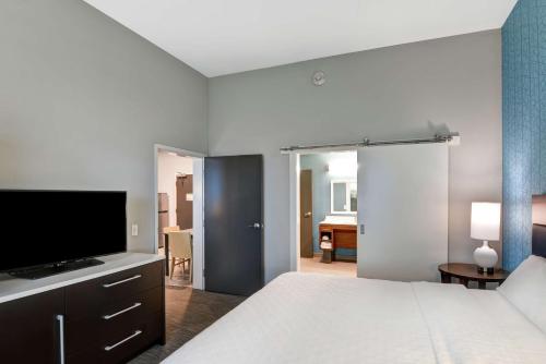 a bedroom with a bed and a flat screen tv at Home2 Suites Pensacola I-10 At North Davis Hwy in Pensacola