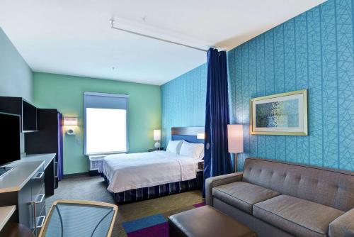 a hotel room with a bed and a couch at Home2 Suites Pensacola I-10 At North Davis Hwy in Pensacola