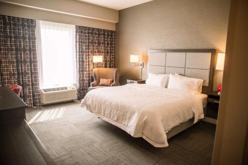 een slaapkamer met een bed, een stoel en een raam bij Hampton Inn-Pontiac in Pontiac