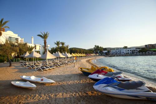 a beach with boats and chairs and umbrellas at Samara Hotel Bodrum Ultra All Inclusive in Torba