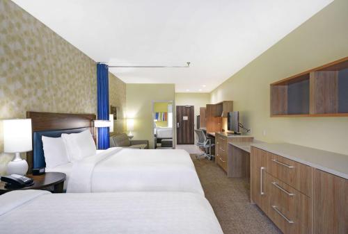a hotel room with two beds and a television at Home2 Suites By Hilton Dallas Desoto in DeSoto