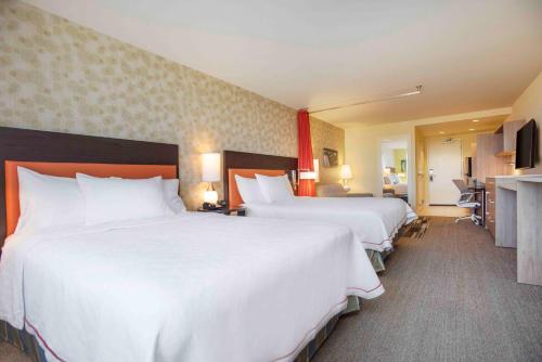 a hotel room with two beds with white sheets at Home2 Suites By Hilton Mishawaka South Bend in Mishawaka