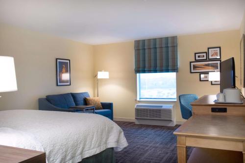 um quarto de hotel com uma cama, uma cadeira e uma secretária em Hampton Inn & Suites Big Rapids, Mi em Big Rapids
