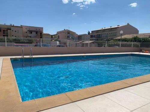 a large blue swimming pool with buildings in the background at Villa à deux pas de la plage Richelieu in Cap d'Agde