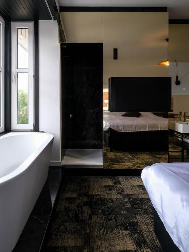 a bathroom with a tub and a bed and a television at Bed & Breakfast Maison Noire Westende-bad incl parking & ontbijt in Middelkerke