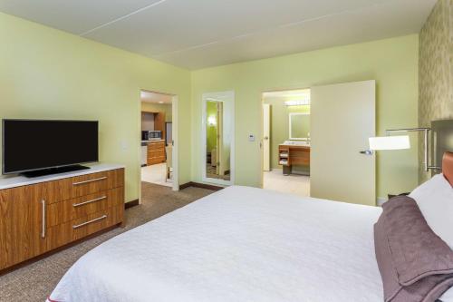 a bedroom with a bed and a flat screen tv at Home2 Suites by Hilton Albany Airport/Wolf Rd in Albany