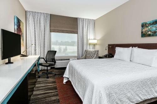 a hotel room with a bed and a desk with a television at Hilton Garden Inn San Marcos in San Marcos