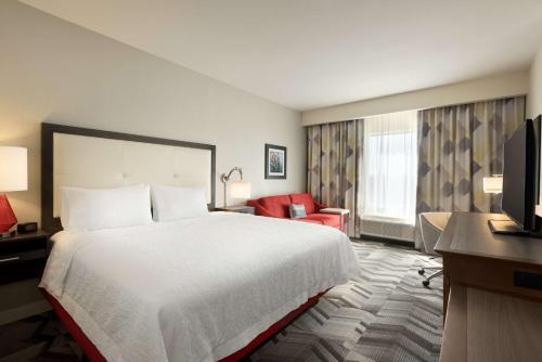 a hotel room with a large bed and a red chair at Hampton Inn by Hilton Spring Hill, TN in Kedron