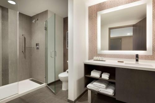 a bathroom with a sink and a toilet and a mirror at Embassy Suites by Hilton Charlotte Uptown in Charlotte