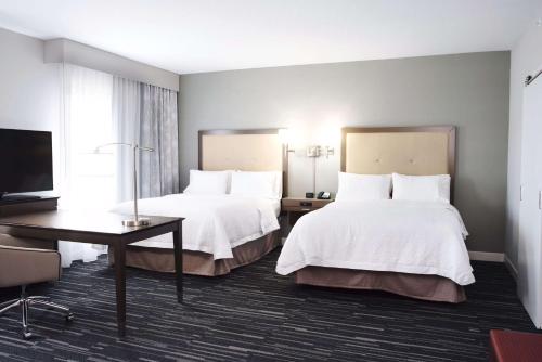 Habitación de hotel con 2 camas, escritorio y TV. en Hampton Inn & Suites Des Moines/Urbandale Ia, en Urbandale