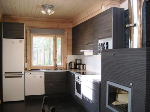 La cocina está equipada con electrodomésticos blancos y fogones. en Holiday Villa Kerimaa 18, en Savonlinna