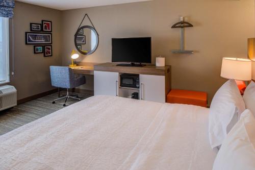 a hotel room with a bed and a desk with a television at Hampton Inn & Suites Wixom/Novi/Detroit, Mi in Wixom